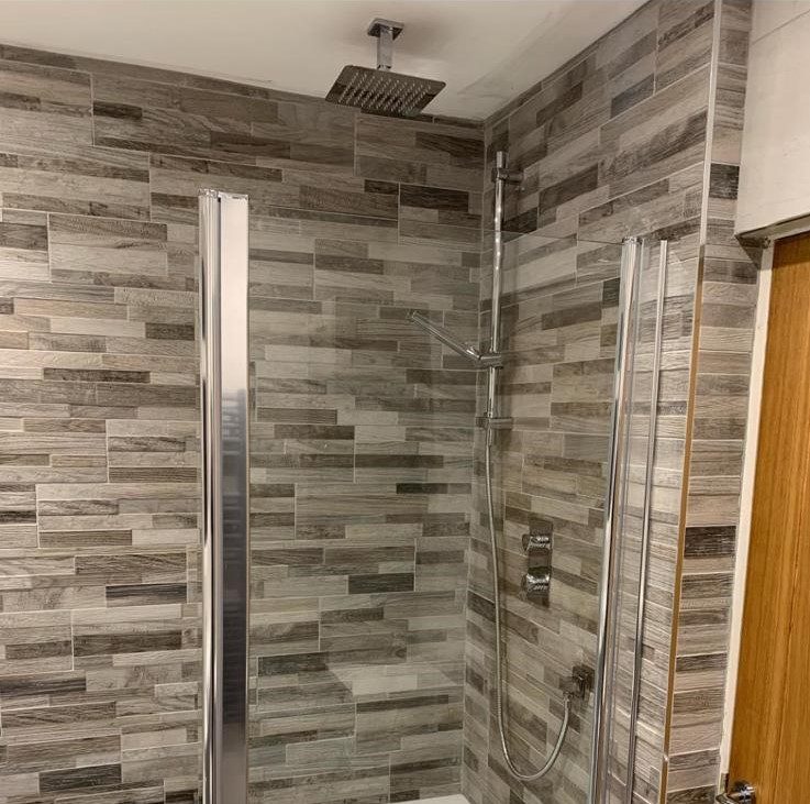 Walk-in shower with wood-effect tiling by JWA Building Services