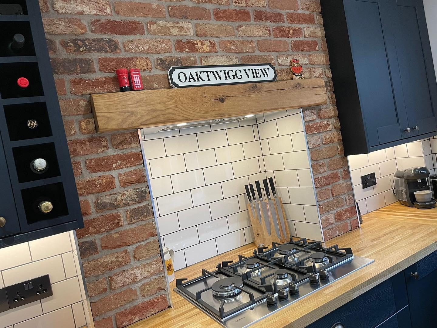 Navy shaker kitchen with exposed brick chimney breast and solid wood worktop by JWA Building Services