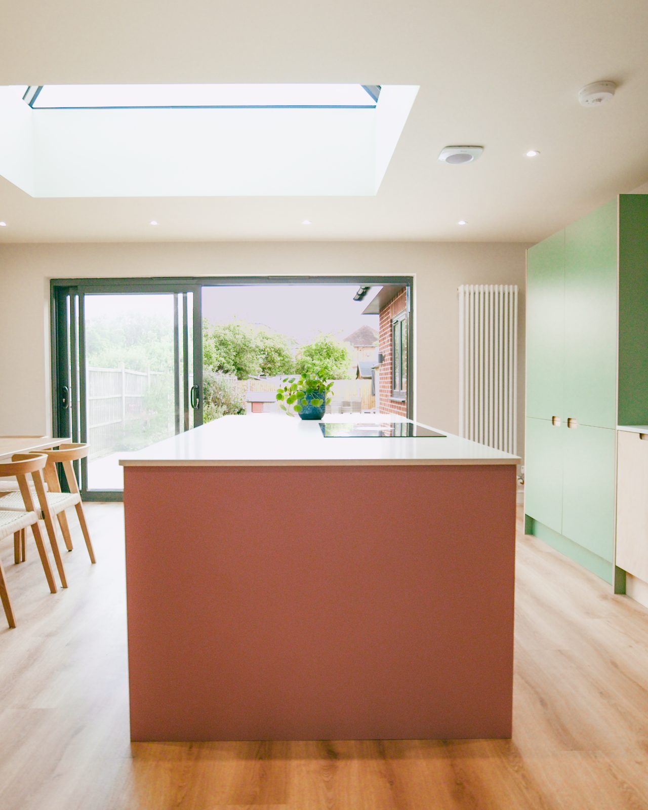 Kitchen island with bi-fold doors to garden by JWA Building Services