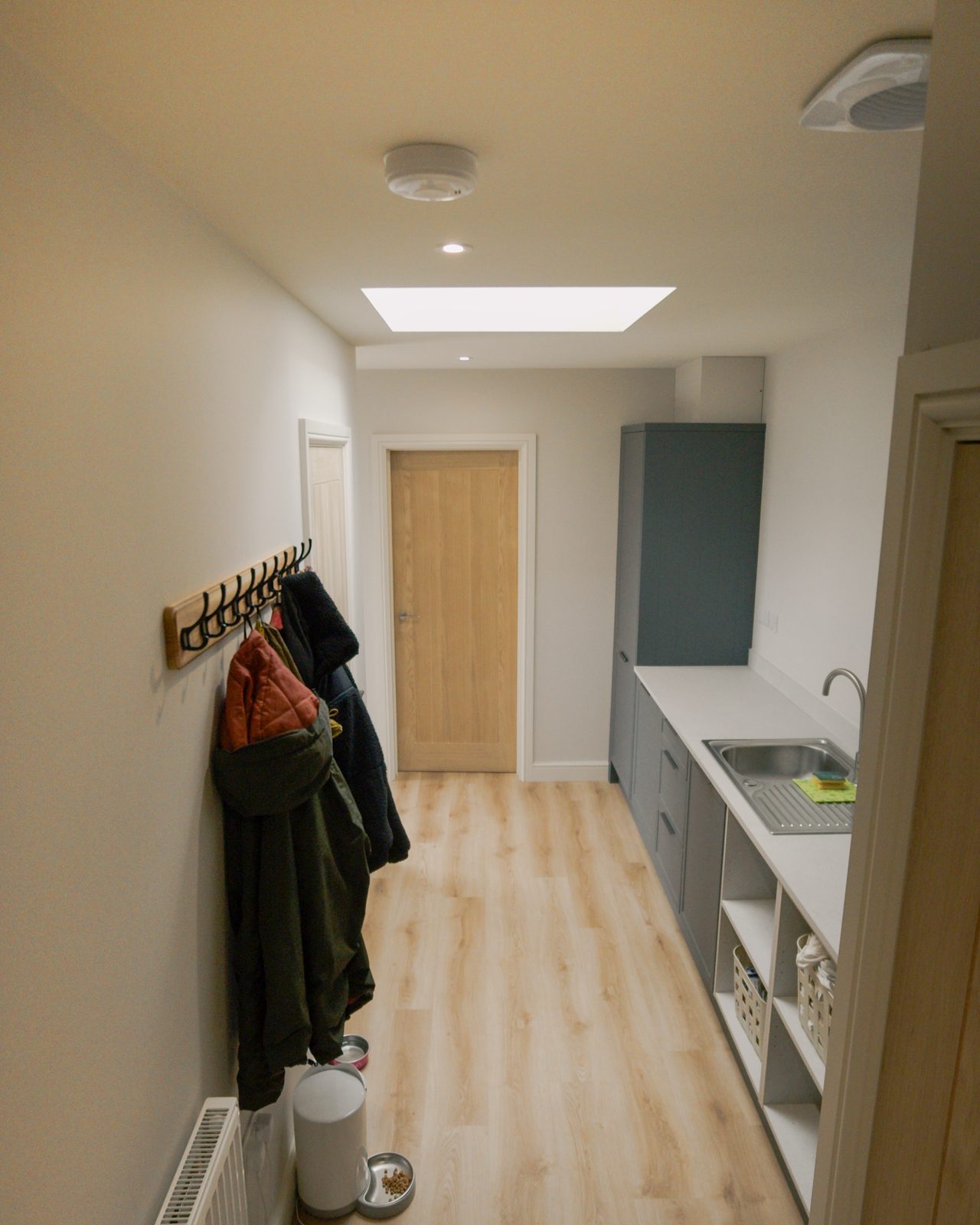 Utility with coat storage and wood flooring by JWA Building Services